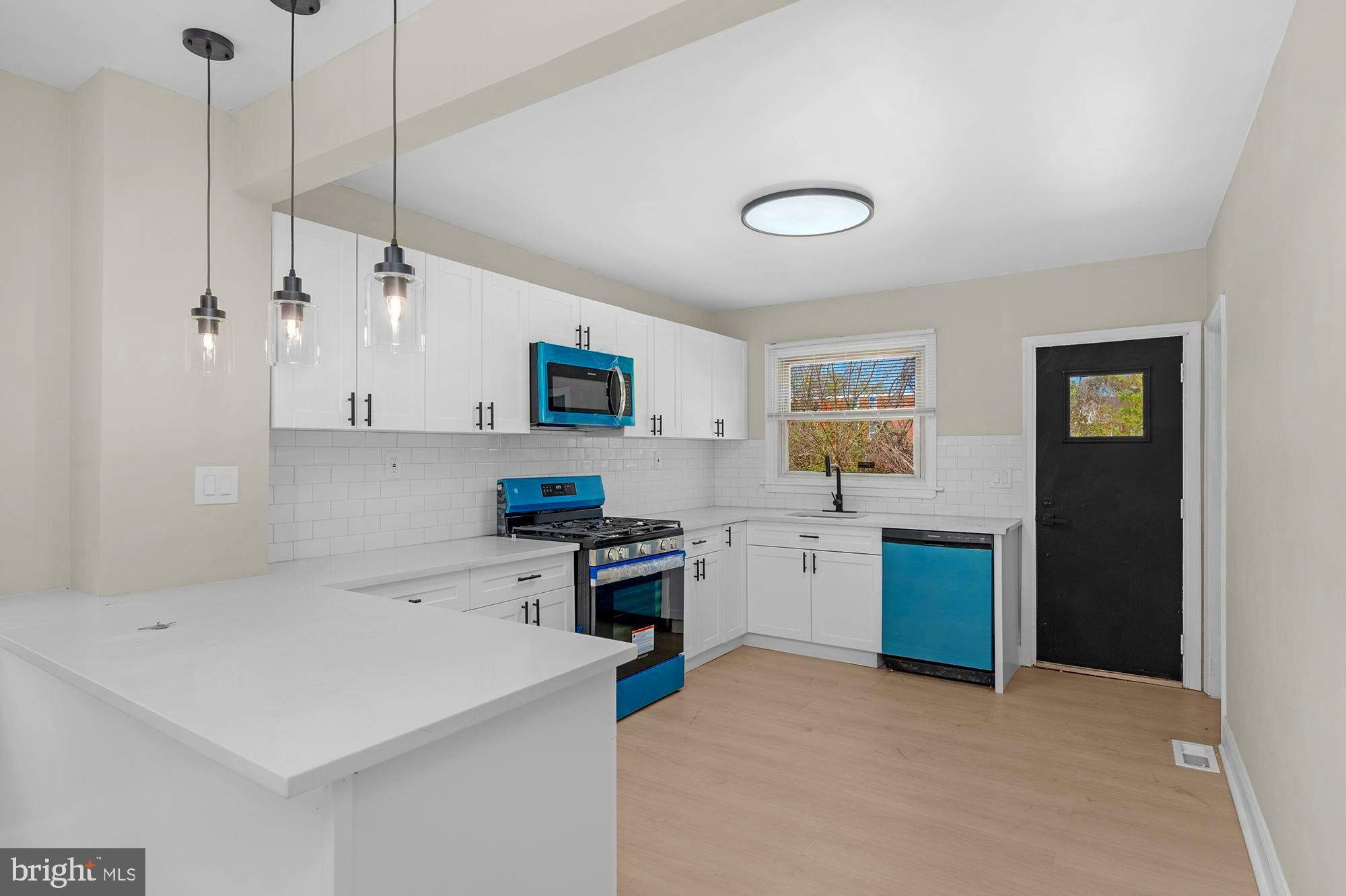 3708 West Cold Spring Lane Baltimore, MD 21215 - Photo 11 of 33 a kitchen with a refrigerator a stove a microwave oven a sink dishwasher with a dining table and chairs