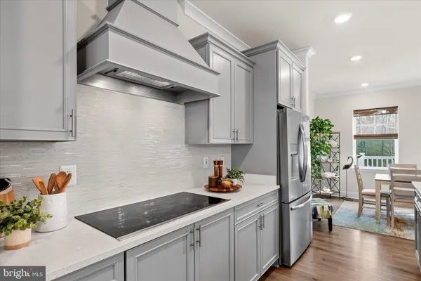 a kitchen with stainless steel appliances granite countertop a refrigerator a sink dishwasher and white cabinets next to a window