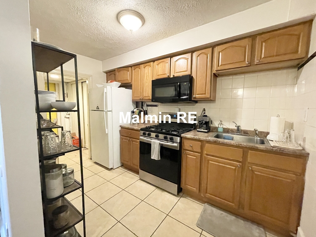 748 East 4th Street, Unit B Boston, MA 02127 - Photo 3 of 11 a kitchen with stainless steel appliances granite countertop a stove a sink and a refrigerator