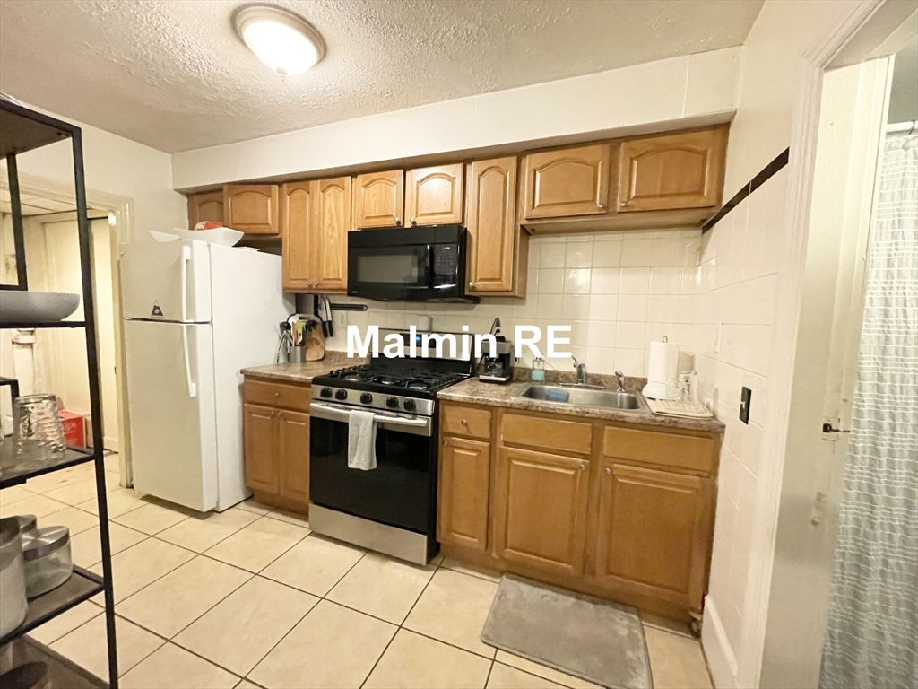 748 East 4th Street, Unit B Boston, MA 02127 - Photo 4 of 11 a kitchen with stainless steel appliances granite countertop a stove a sink and a refrigerator