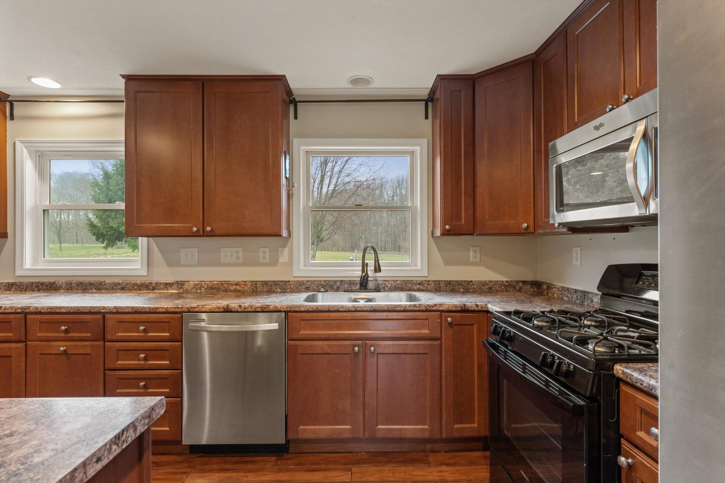 7692 North Emery Road Rolling Prairie, IN 46371 - Photo 18 of 69 a kitchen with stainless steel appliances granite countertop a stove a sink and a microwave