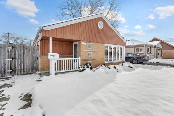 a front view of a house with a yard covered in snow