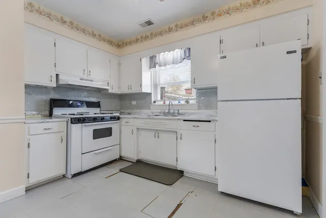 a kitchen with white cabinets and white appliances