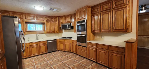 a kitchen with granite countertop stainless steel appliances a refrigerator and cabinets