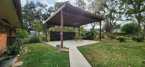 a view of a backyard with table and chairs potted plants and large tree