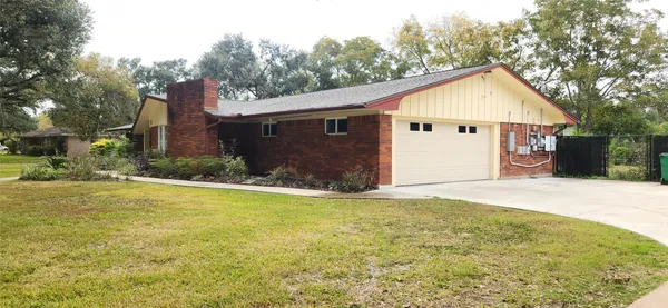 a view of house with backyard and trees in the background