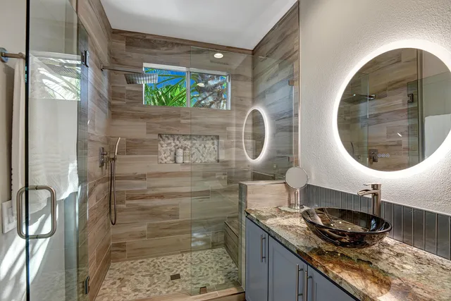 a bathroom with a granite countertop sink a mirror and a shower