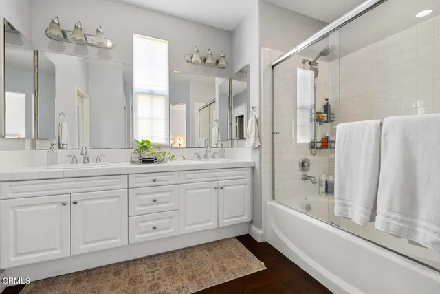 a bathroom with a double vanity sink a mirror a bathtub and shower