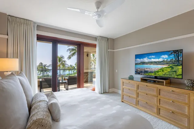 a bedroom with a large bed and a chandelier fan