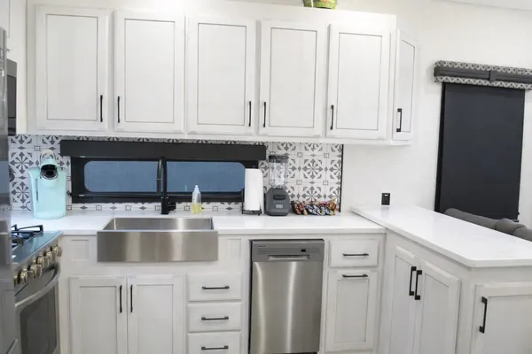 a kitchen with white cabinets and sink