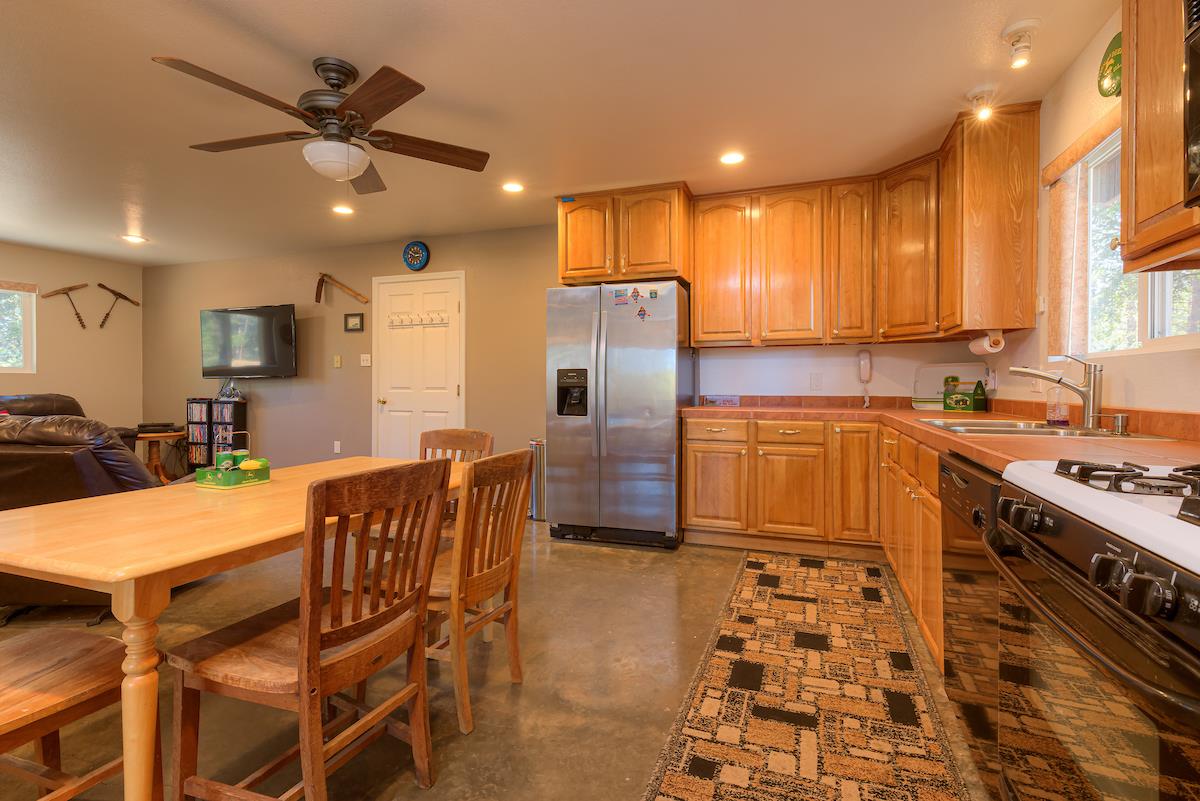 179 Elams Ranch Road Oroville, CA 95966 - Photo 9 of 52 a kitchen with stainless steel appliances granite countertop a sink a stove a refrigerator cabinets and a dining table with wooden floor
