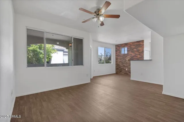 a view of an empty room with a window and wooden floor