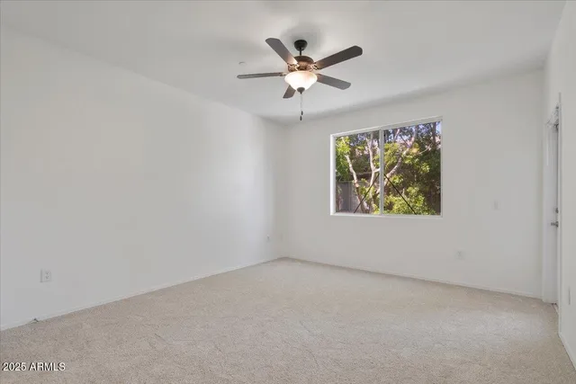 an empty room with window and ceiling fan