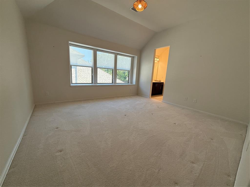 5212 Troupe Road McKinney, TX 75071 - Photo 19 of 38 Vaulted ceiling room featuring light-toned carpeting, a multi-pane window, and a visible doorway leading to an adjoining space with a dark wood-finish vanity