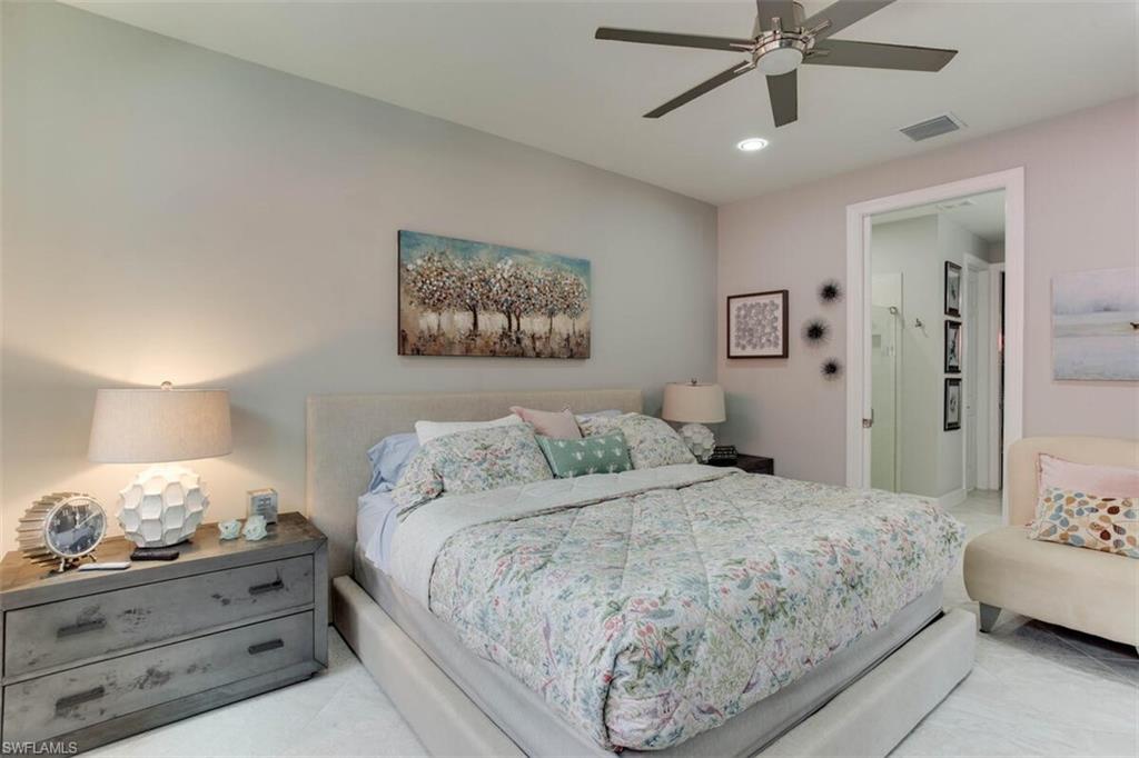 7682 Jacaranda Lane Naples, FL 34114 - Photo 19 of 44 a bedroom with a large bed and a chandelier