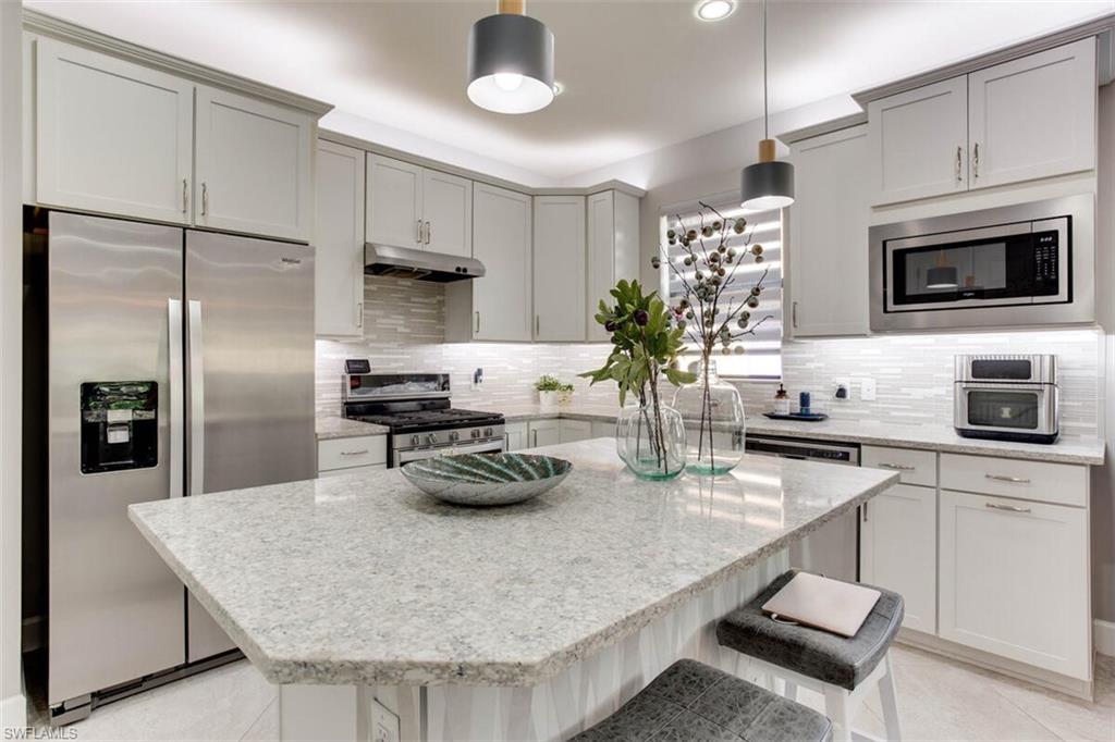 7682 Jacaranda Lane Naples, FL 34114 - Photo 7 of 44 a kitchen with stainless steel appliances granite countertop a sink a stove and a refrigerator
