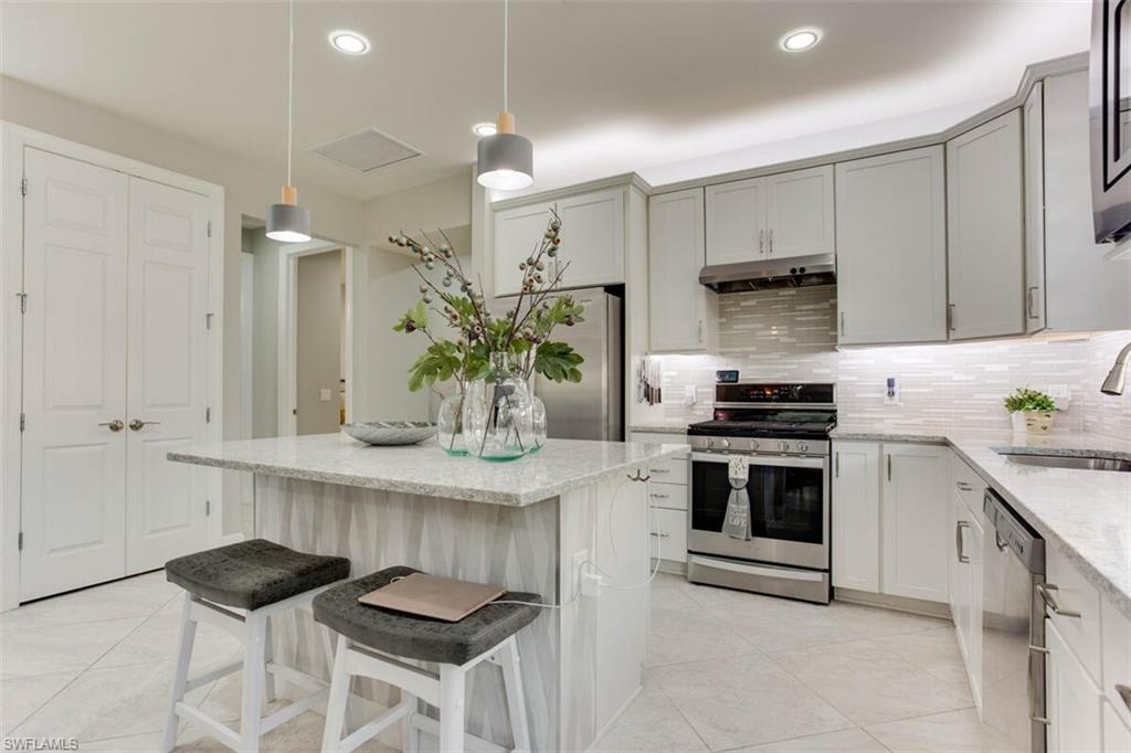7682 Jacaranda Lane Naples, FL 34114 - Photo 10 of 44 a kitchen with kitchen island granite countertop a sink cabinets and stainless steel appliances