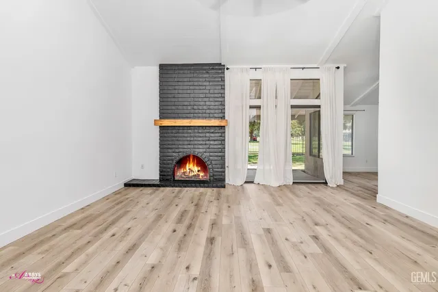 a view of empty room with wooden floor and fireplace