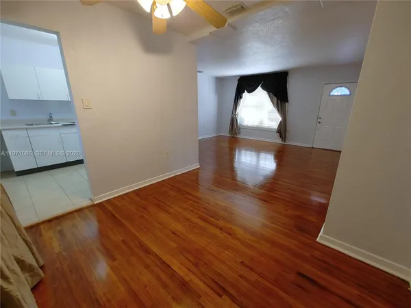 a view of empty room with wooden floor and window