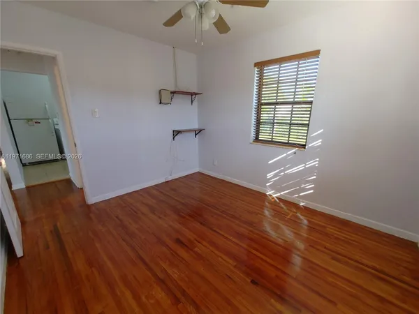 an empty room with wooden floor chandelier fan and windows