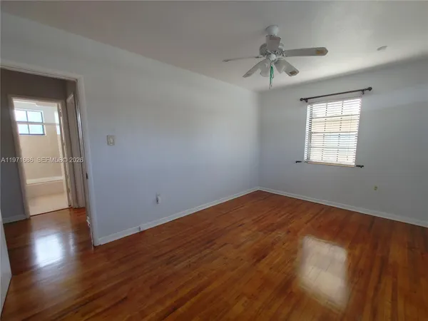 an empty room with wooden floor fan and windows