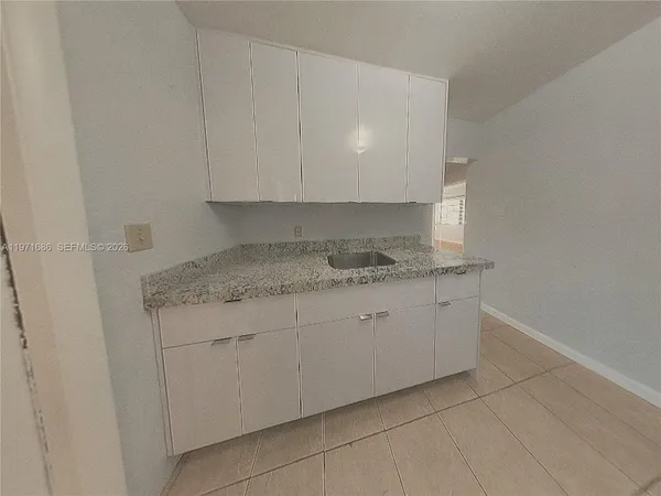 a kitchen with granite countertop white cabinets and a sink