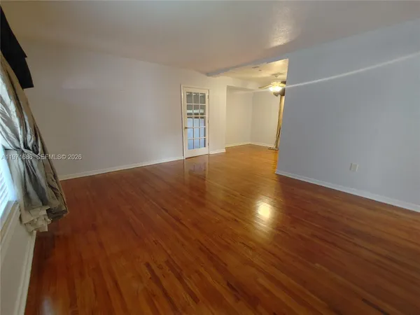 an empty room with wooden floor and windows