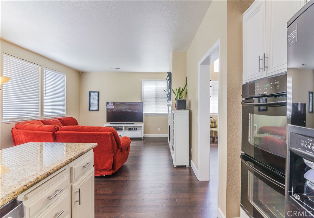 743 Orchard Loop Azusa, CA 91702 - Photo 18 of 39 a kitchen with stainless steel appliances kitchen island granite countertop a refrigerator a stove and a sink with wooden floor