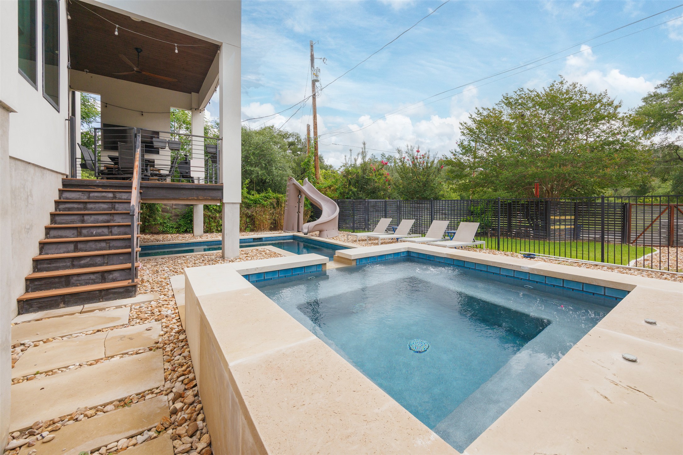 4103 Ridgelea Drive Austin, TX 78731 - Photo 3 of 26 An inviting backyard oasis offers a sparkling pool with a slide and a shaded deck for outdoor enjoyment.