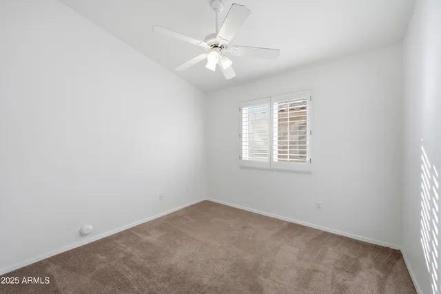 an empty room with a window and a fan