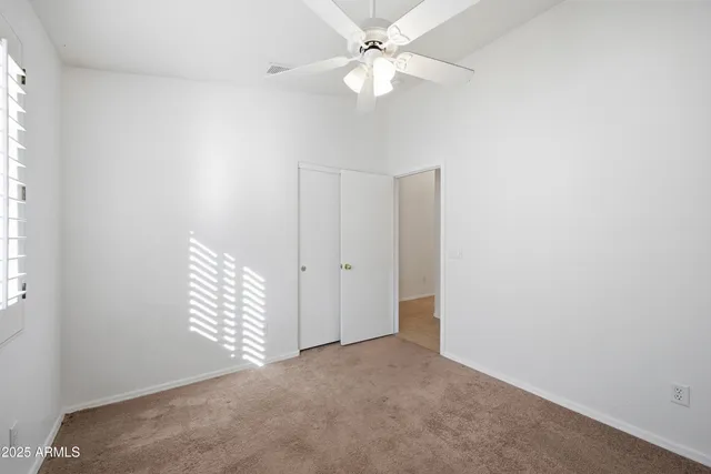 an empty room with windows and fan