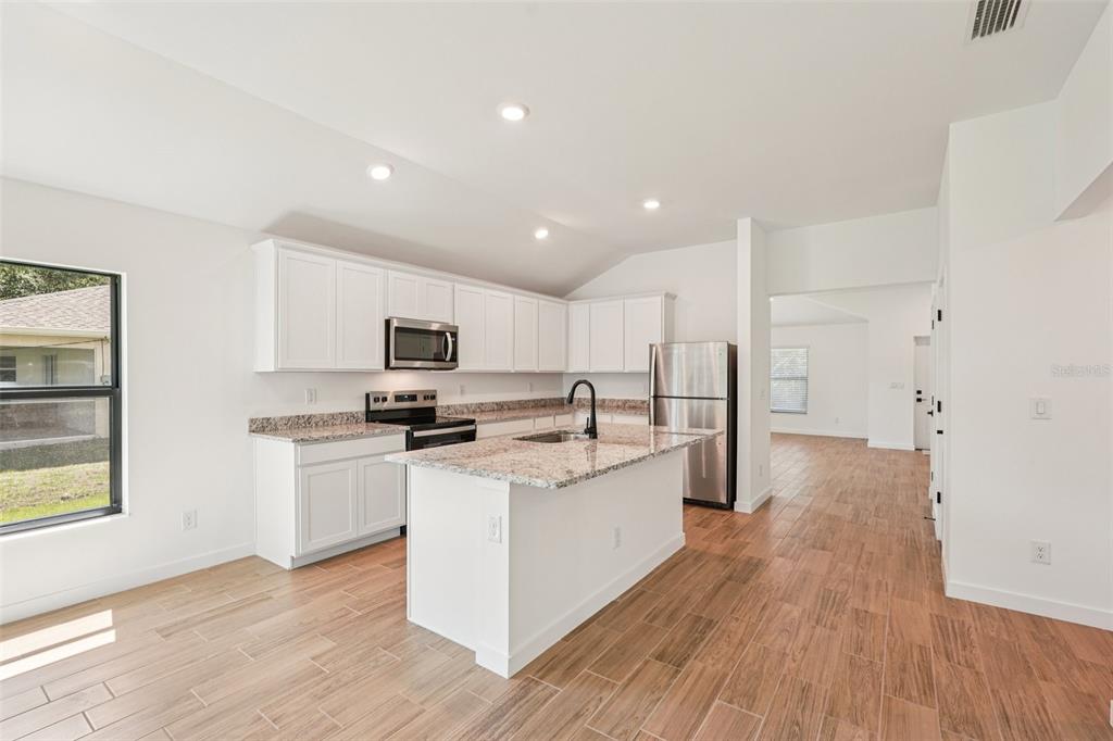 5237 Aberback Street North Port, FL 34291 - Photo 22 of 46 a kitchen with stainless steel appliances a stove top oven a sink a refrigerator white cabinets and wooden floor