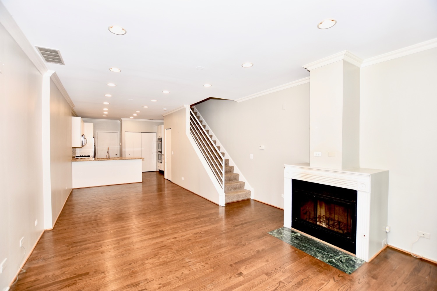 1801 West Diversey Parkway, Unit 18 Chicago, IL 60614 - Photo 5 of 32 a view of an empty room with wooden floor and a kitchen