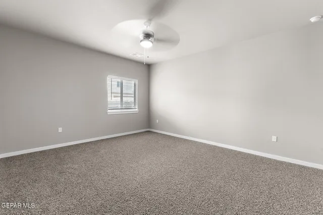 a view of an empty room with a chandelier fan