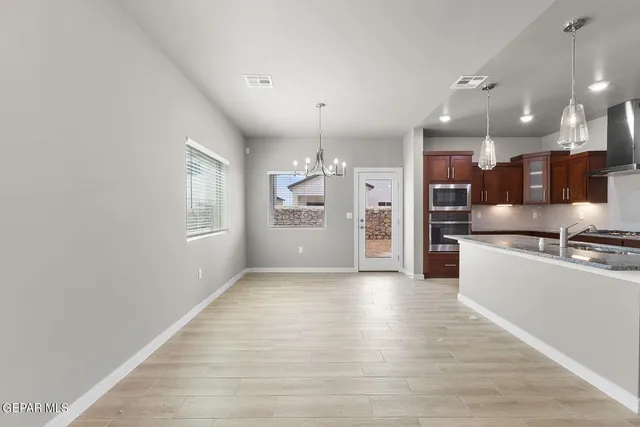 a large kitchen with stainless steel appliances kitchen island a large counter top and a wooden floors
