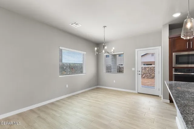 an empty room with chandelier fan and windows