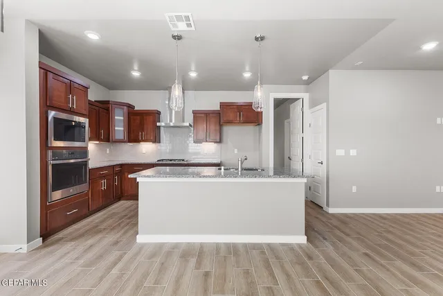 a large kitchen with stainless steel appliances a large counter top a stove and a wooden floors