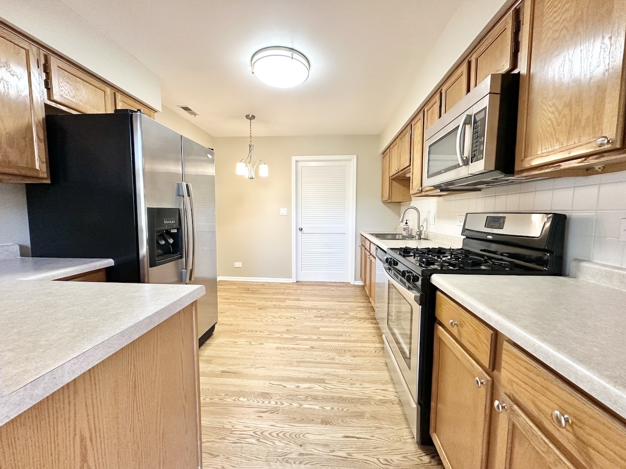 1193 Ranchview Court Buffalo Grove, IL 60089 - Photo 3 of 19 a kitchen with stainless steel appliances granite countertop a refrigerator a stove and a sink with wooden floor