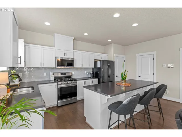 a kitchen with stainless steel appliances granite countertop a sink a stove and a refrigerator