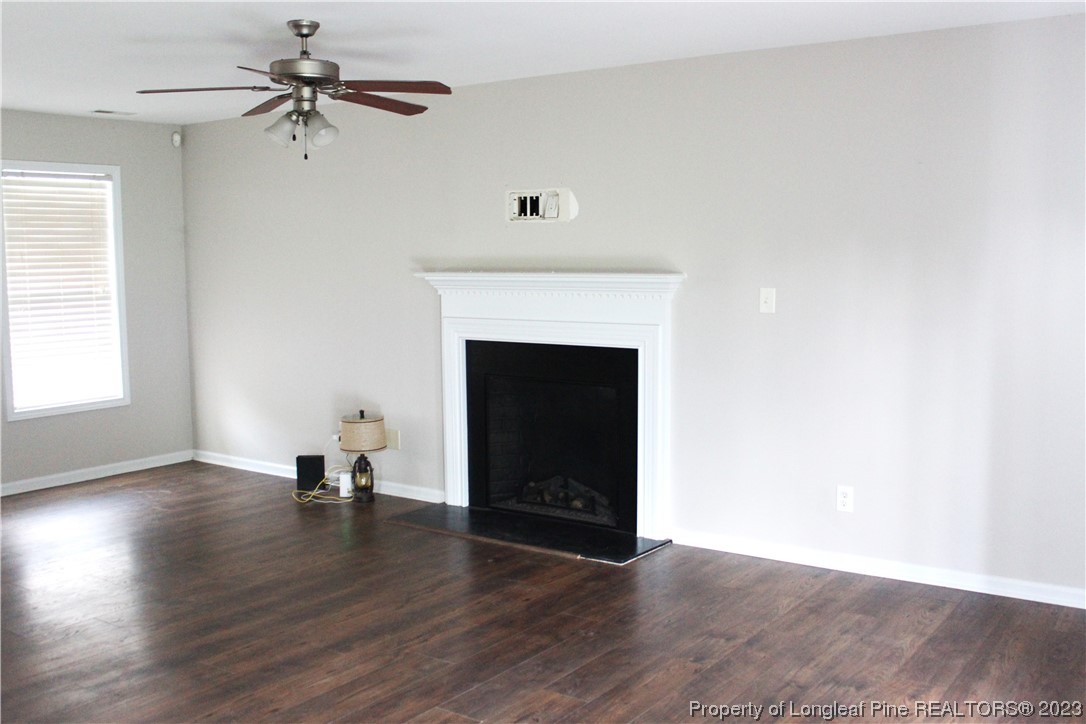678 Cape Fear Road Raeford, NC 28376 - Photo 3 of 30 an empty room with wooden floor fireplace and windows