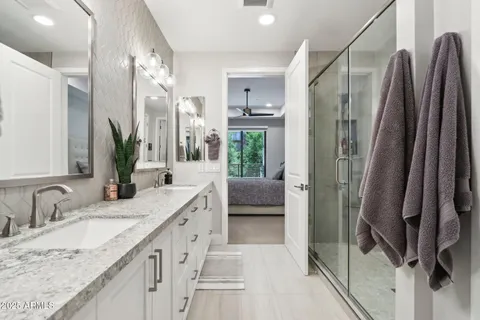 a bathroom with a granite countertop double vanity sink and mirror