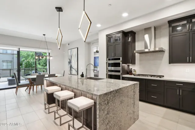 a kitchen with stainless steel appliances kitchen island granite countertop a table chairs sink and wooden cabinets