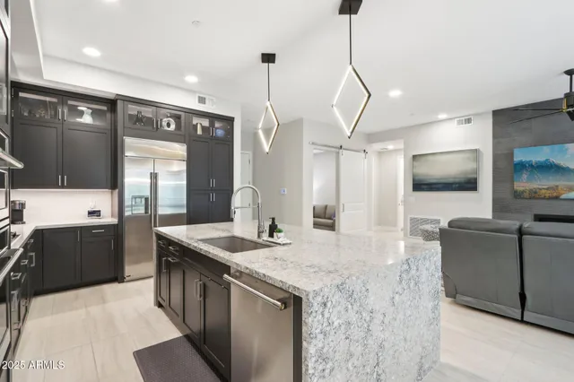 a kitchen with stainless steel appliances kitchen island granite countertop a sink stove and refrigerator