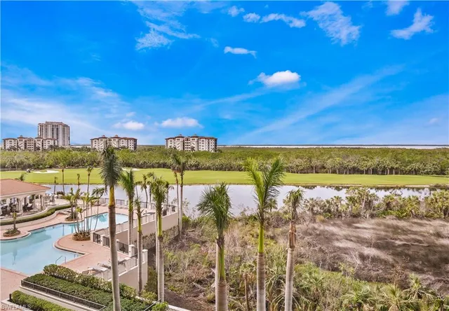 a view of pool with lawn chairs and palm tree