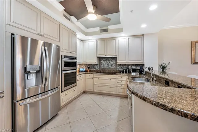 a kitchen with granite countertop a refrigerator and stainless steel appliances