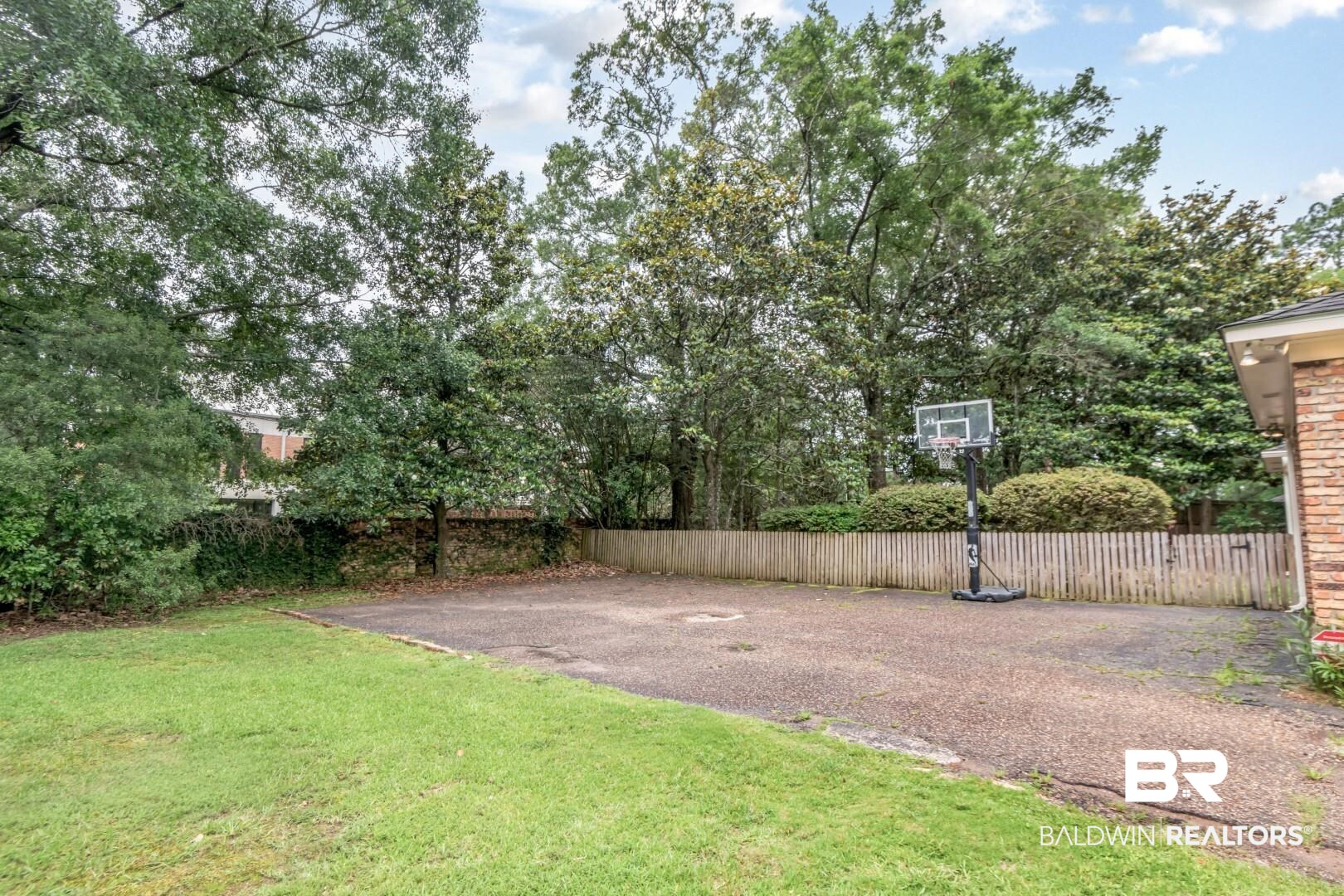 4776 Falls Church Road Mobile, AL 36608 - Photo 39 of 45 Expansive paved area bordered by a wood fence, mature trees, and a manicured lawn