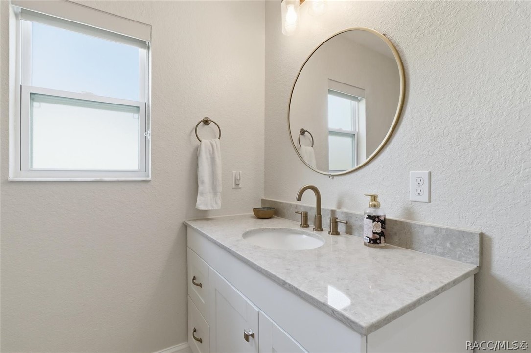 4099 West Ridge Court Dunnellon, FL 34433 - Photo 31 of 49 Like new guest bathroom with wood cabinets, quartz counter with sink. Nice faucets, mirror and lights. Features spacious walk in tiled shower.