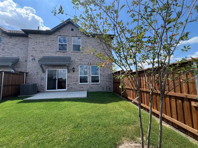 a view of a yard in front of a brick house with a large tree