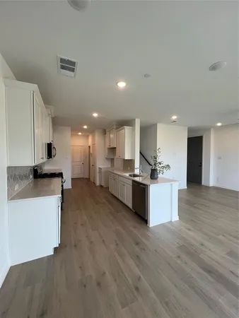 a large kitchen with stainless steel appliances kitchen island a large counter top and a wooden floors
