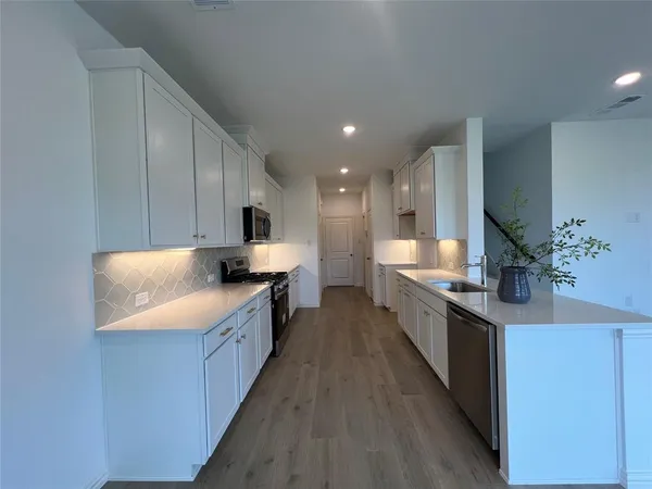 a large kitchen with stainless steel appliances a sink a counter top space cabinets and a potted plant